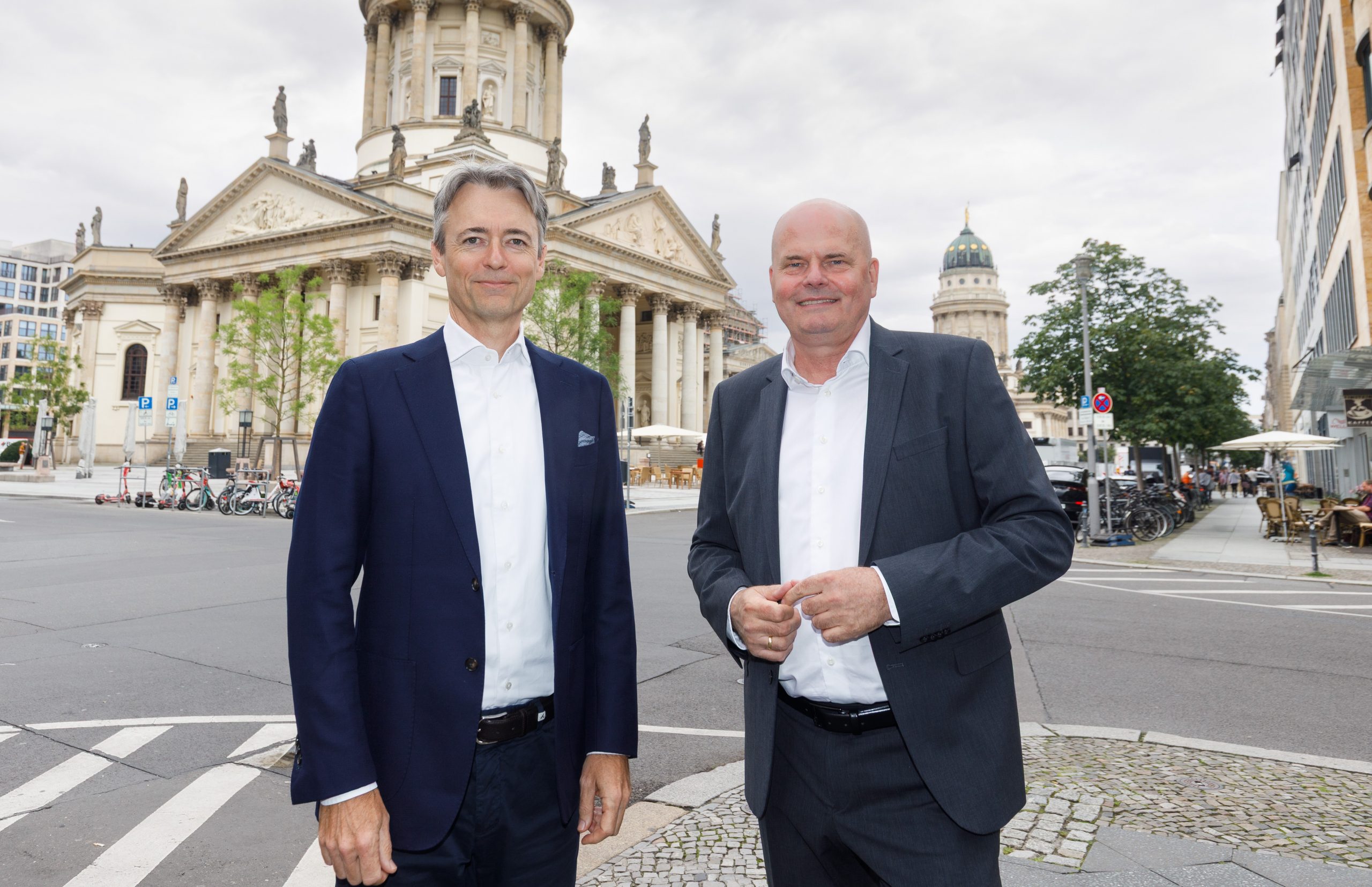 Bernd Bertram und Frank Westphal stehen nach der Unterschrift der Vereinbarung an dem Gendarmenmarkt Berlin und lächeln in die Kamera.