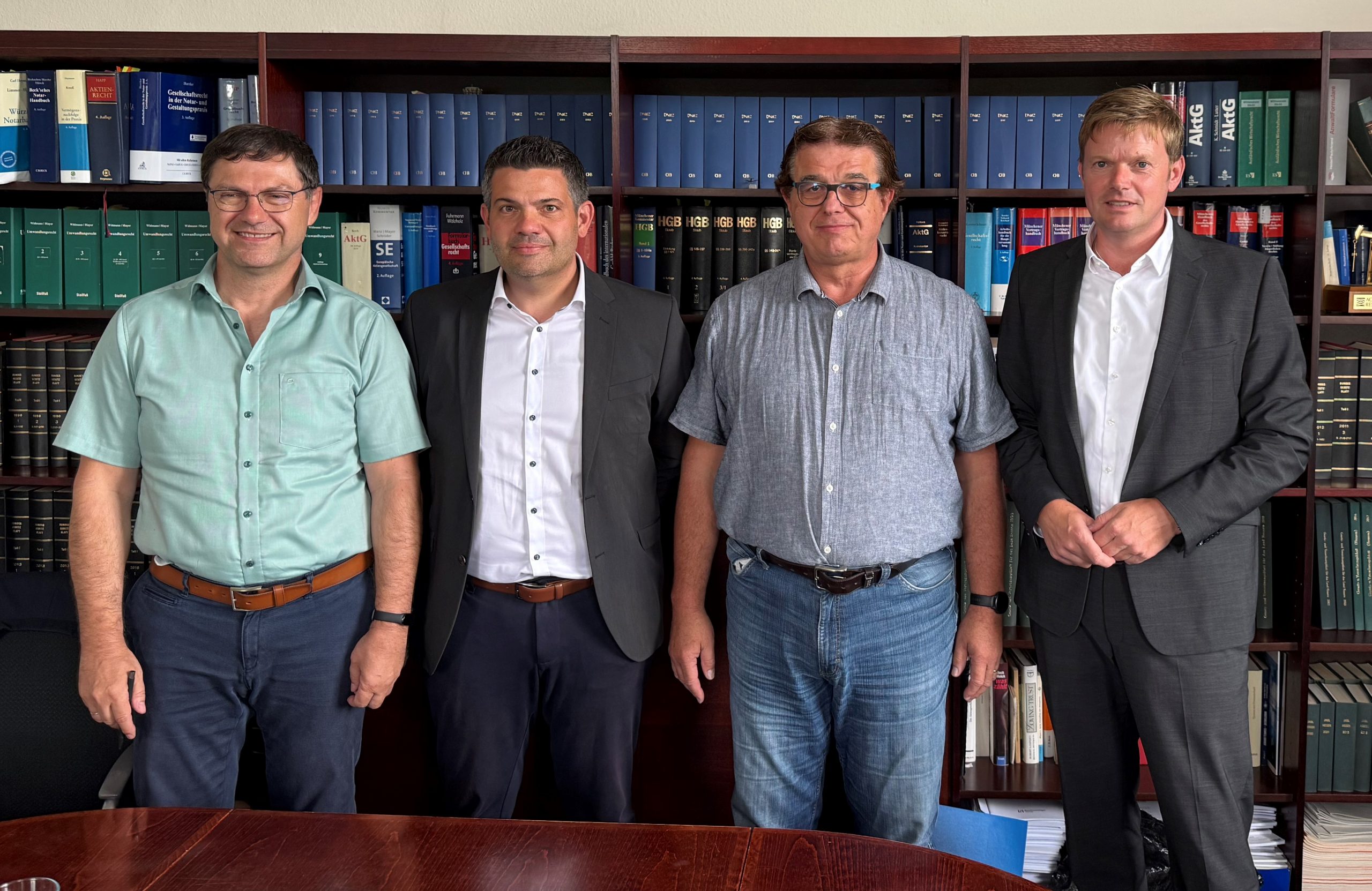 Ein Foto, welches bei der Unterzeichnung der Übernahmedokumente aufgenommen wurde. Udo Flory und Andreas Hübner von der SP Consulting GmbH sind dabei neben Manuel Dietz und André Rottstegge, bei von Actemium, abgebildet. Sie lächeln allesamt in die Kamera.